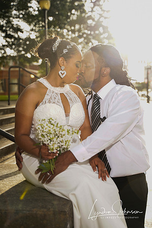 Wedding portrait of couple, sitting on wall, with liens flare,